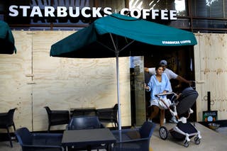 2024年7月3日、メキシコのプラヤ・デル・カルメンで、ハリケーン・ベリルの到来前に閉店したスターバックス・コーヒーの店舗から出てくる人々。